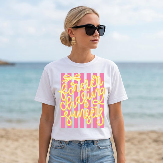Sunset Graphic Tee Retro Beach Shirt Vintage Summer Tee Beach Vacation Shirt Forever Chasing Sunsets Design Yellow Cursive Lettering Pink White Striped Pattern Seventies Inspired Fashion Coastal Lifestyle Apparel Comfort Colors Fabric Soft