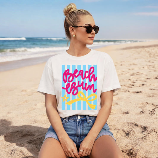 White Graphic Tee Women Pink Script Lettering Beach Bum Design Blue Striped Pattern Yellow Bow Detail Summer Vacation Shirt Casual Resort Wear Tropical Travel Top Cruise Outfit Essential Poolside Casual Clothing Soft Cotton Blend Relaxed
